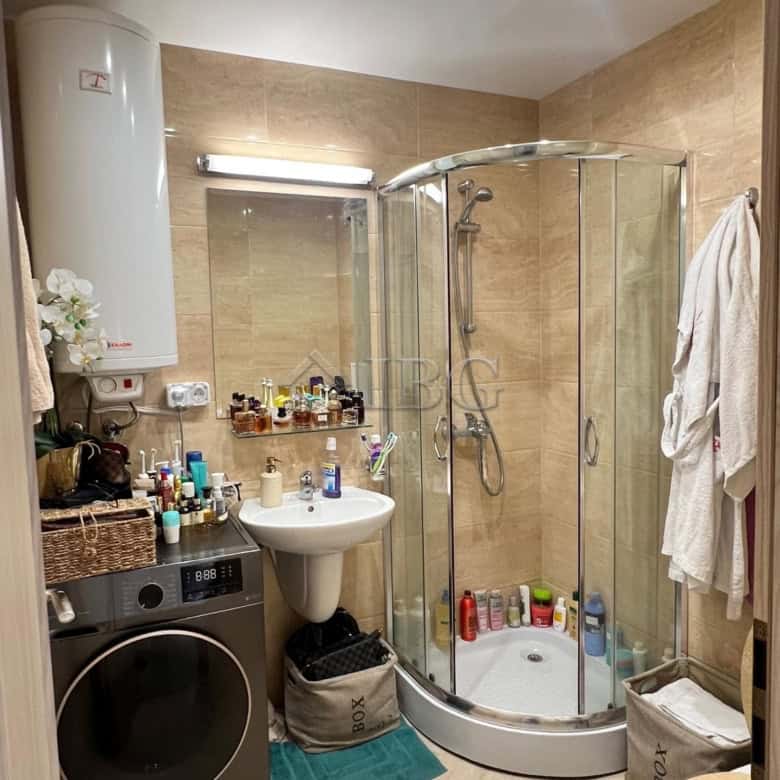 Bright bathroom with shower, washing machine, and personal care products.