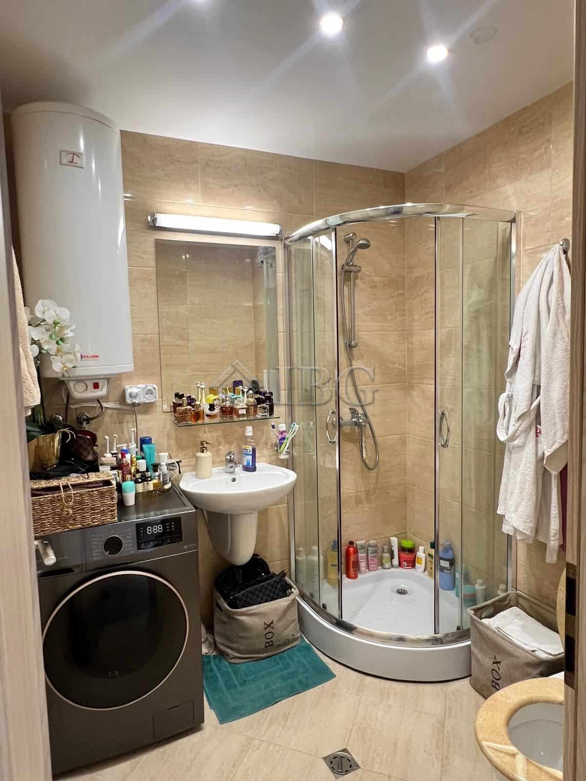 Bright bathroom with shower, washing machine, and personal care products.