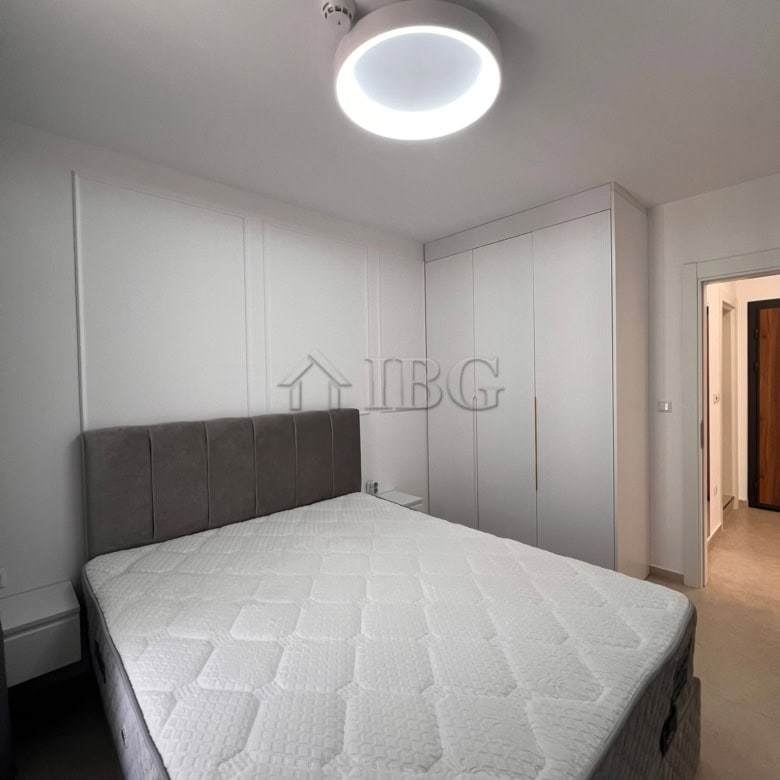 Bright bedroom with white walls, gray headboard, and modern ceiling light fixture.