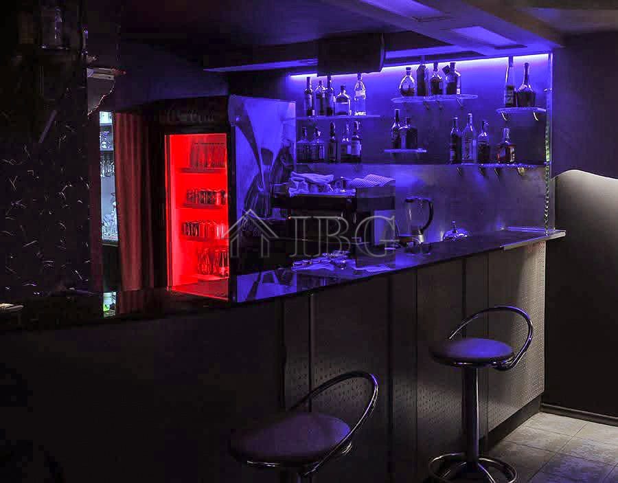 Bar with illuminated shelves and seating in a commercial premises.