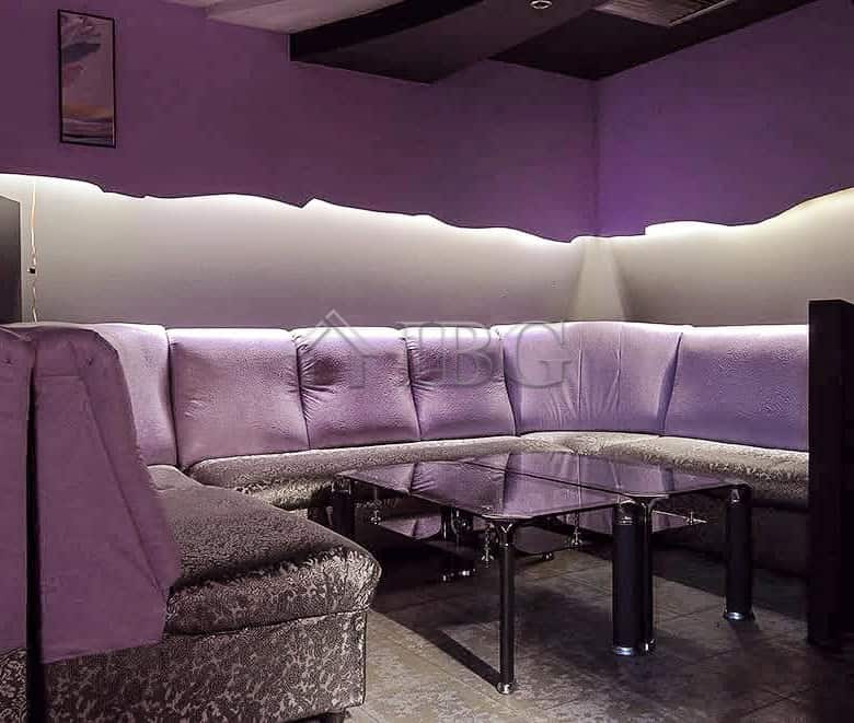 Interior of commercial premises featuring a stylish lounge with purple lighting and comfortable seat.