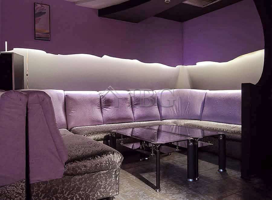 Interior of commercial premises featuring a stylish lounge with purple lighting and comfortable seat.