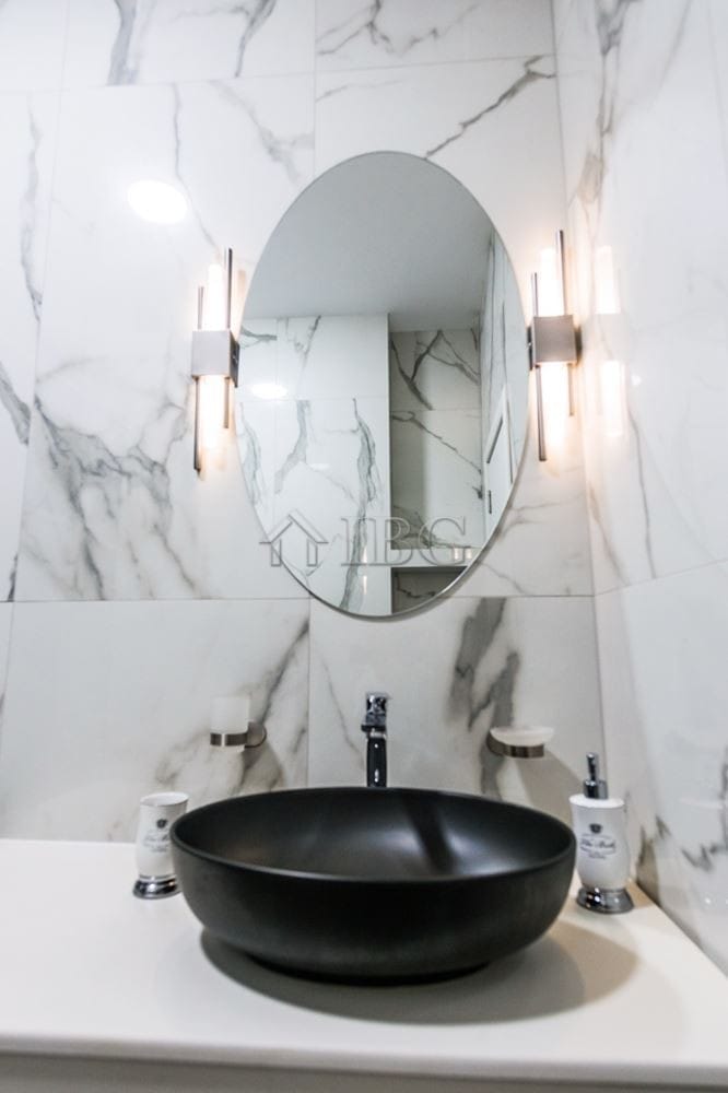 Modern bathroom with marble walls and stylish lighting.