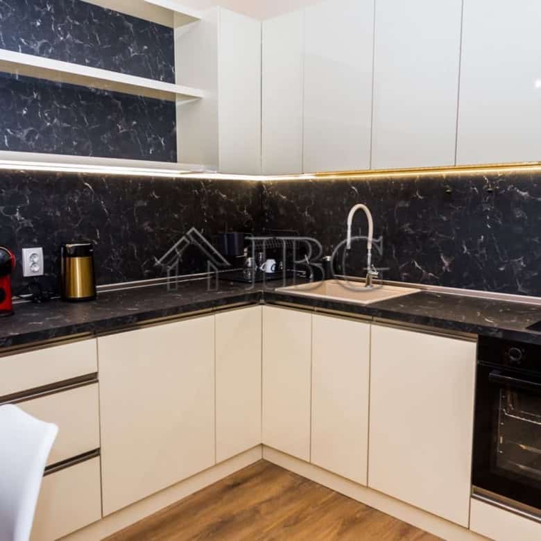 Modern kitchen with black marble countertops and white cabinetry in Lazur District, Burgas.