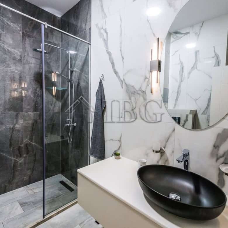 Modern bathroom in Lazur District, Burgas with stylish black sink and marble walls.