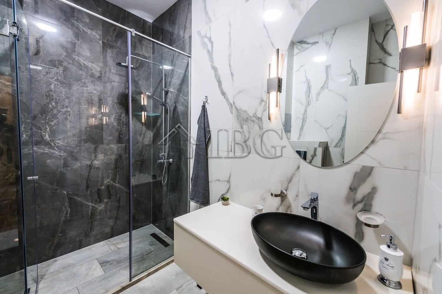 Modern bathroom in Lazur District, Burgas with stylish black sink and marble walls.