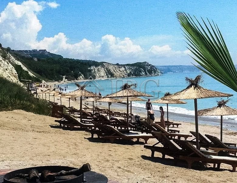 Bright beach scene at Lighthouse Golf Resort, Balchik with sun loungers and scenic coastline.