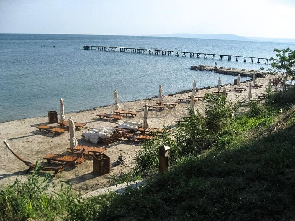 Seaside beach with sun loungers, umbrellas, and a wooden pier at Lighthouse Golf & Spa Resort near B.