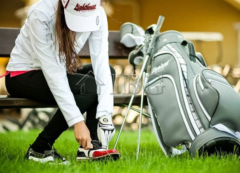 Woman preparing golf clubs outside a golf course, showcasing luxury living.
