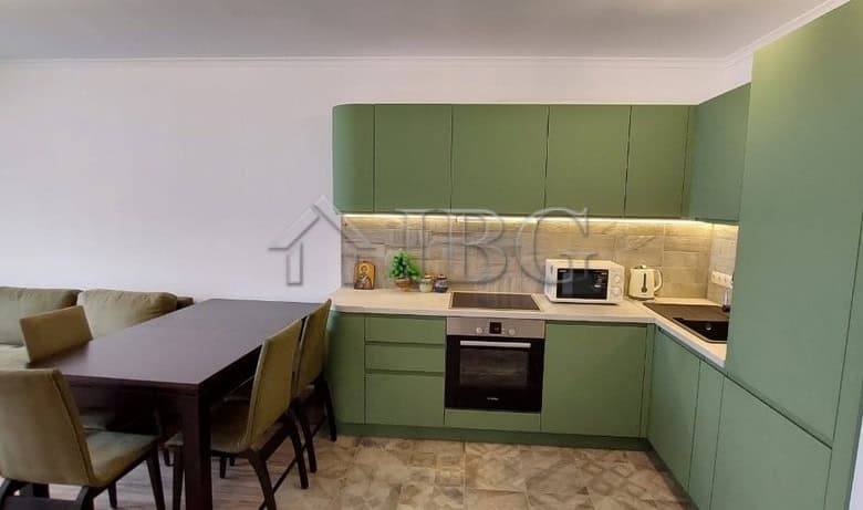 Green kitchen with integrated appliances and dining table in Sveti Vlas apartment.