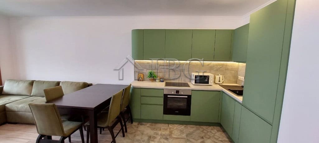 Green kitchen with integrated appliances and dining table in Sveti Vlas apartment.