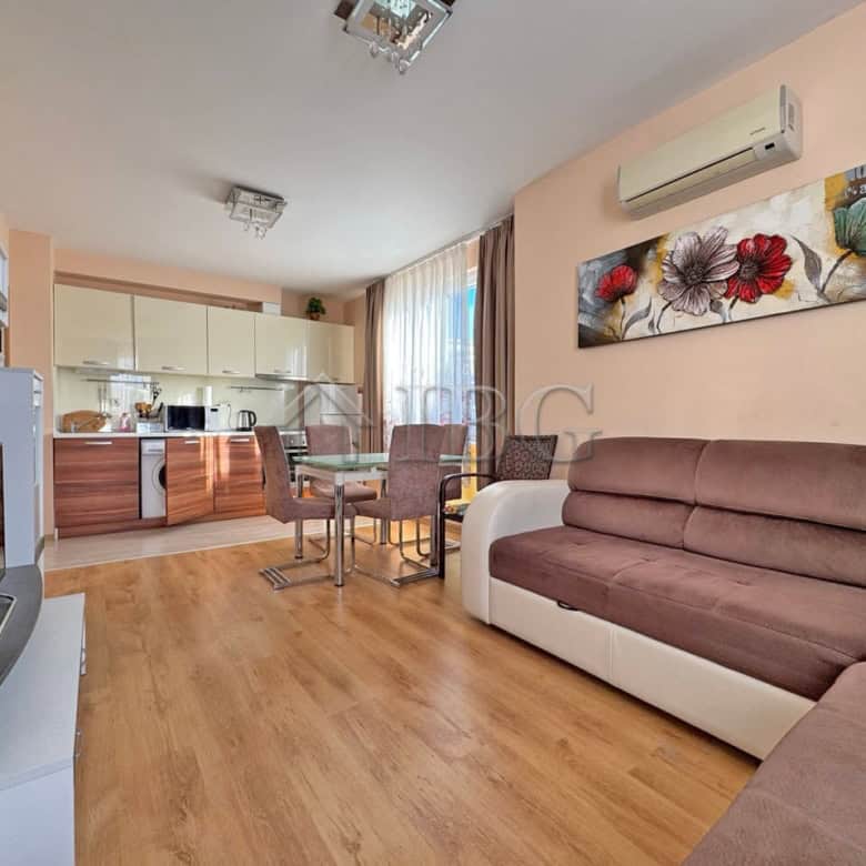 Bright living room with sofa, dining area, and open kitchen in Messembria Palace, Sunny Beach.