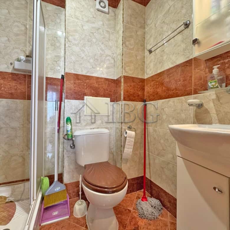 Bright bathroom with shower, toilet, and sink in Nessebar Fort Club apartment.