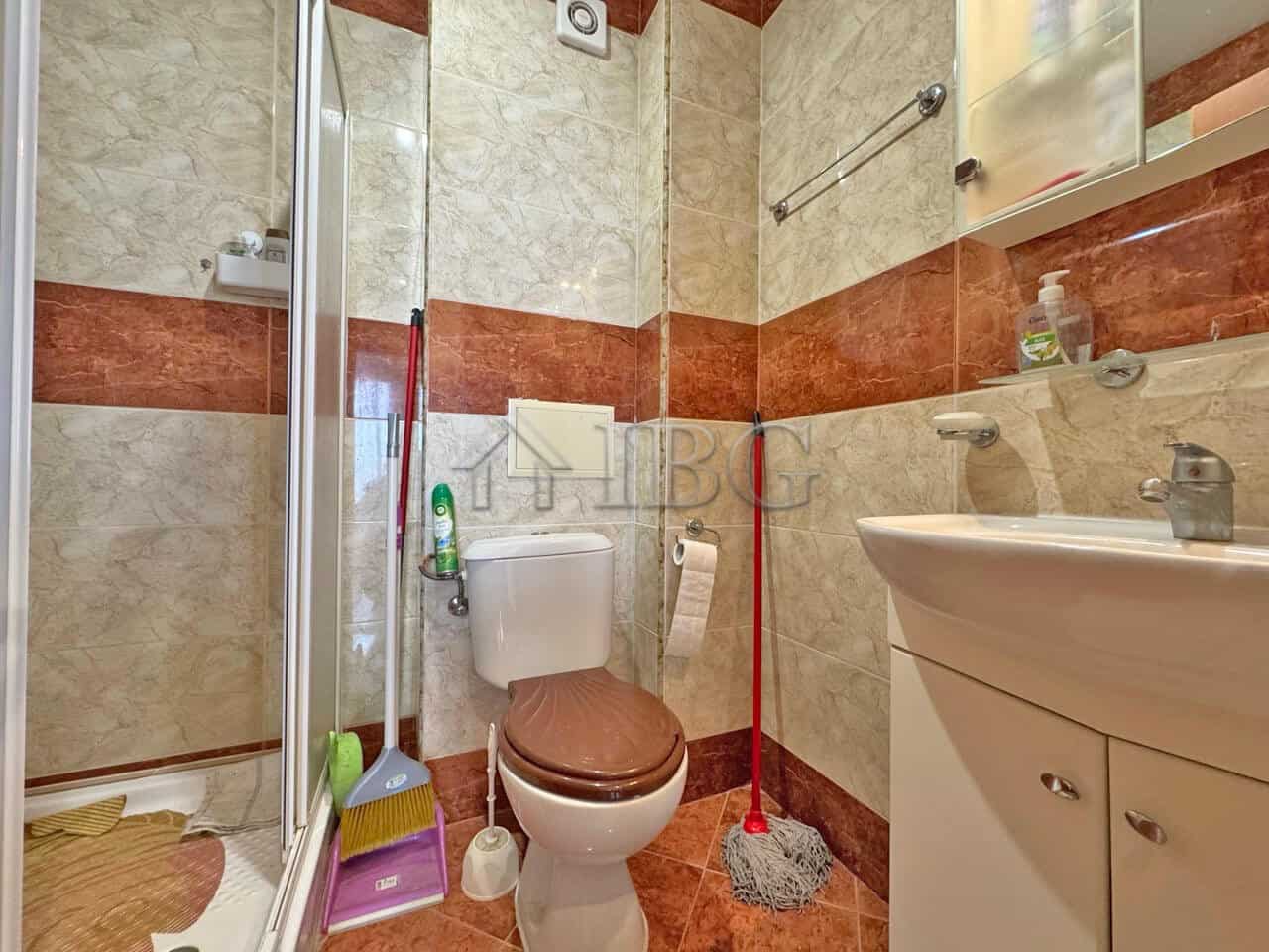 Bright bathroom with shower, toilet, and sink in Nessebar Fort Club apartment.