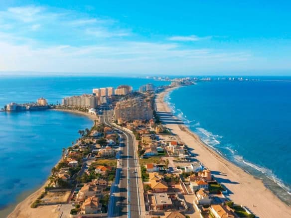An aerial view of a vibrant coastal city with sandy beaches and modern buildings along the shoreline.