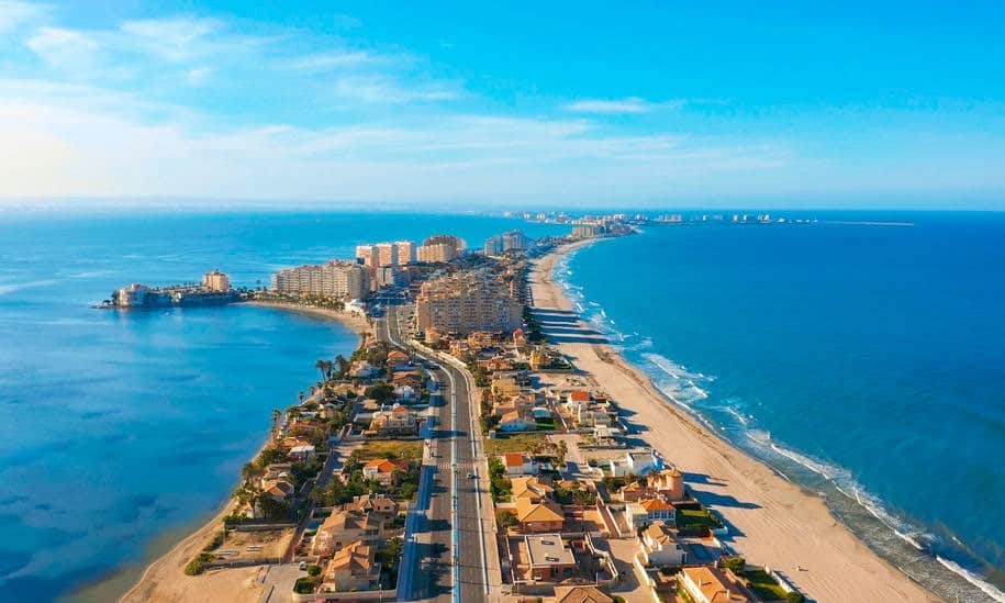 An aerial view of a vibrant coastal city with sandy beaches and modern buildings along the shoreline.