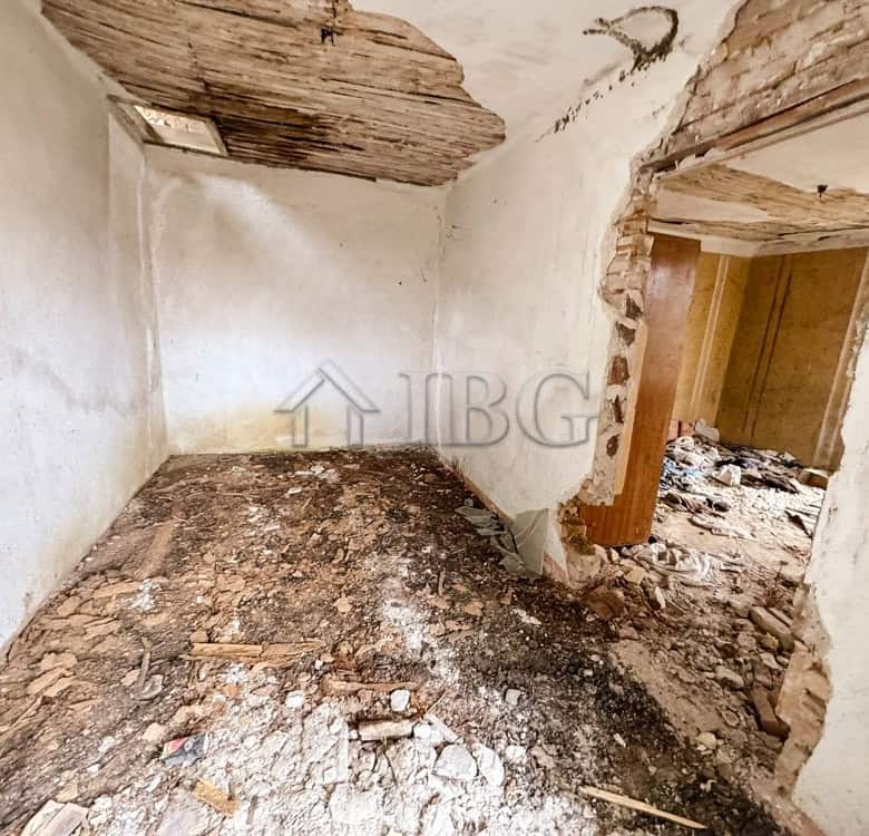 Interior of a partially renovated house with exposed brick and damaged ceiling.