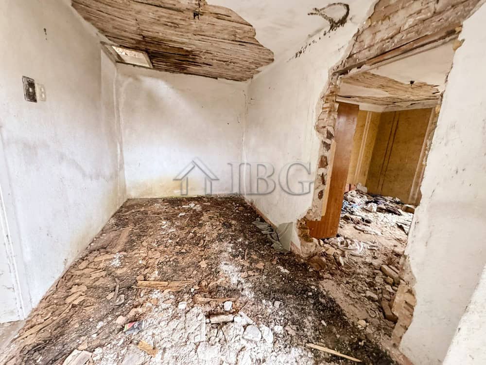 Interior of a partially renovated house with exposed brick and damaged ceiling.