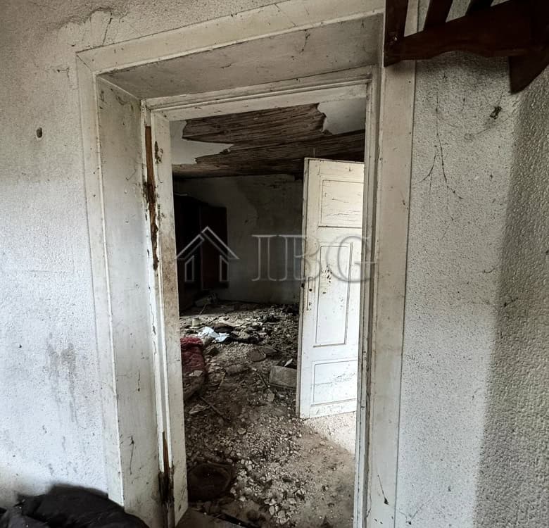 Interior view of a renovation project with a large garden and potential for development.