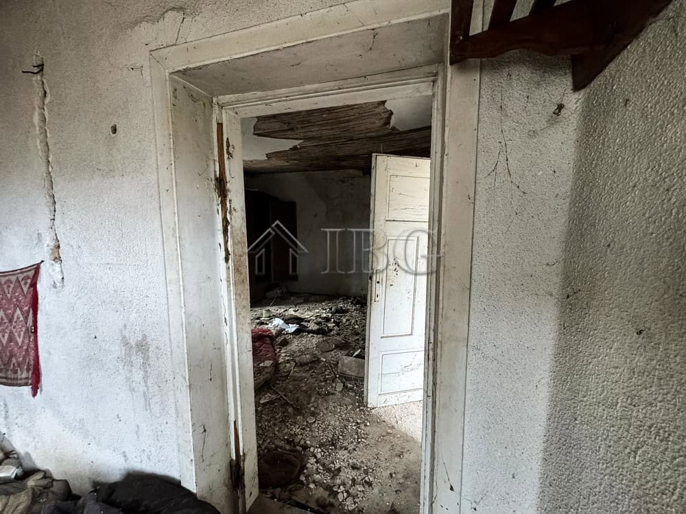 Interior view of a renovation project with a large garden and potential for development.