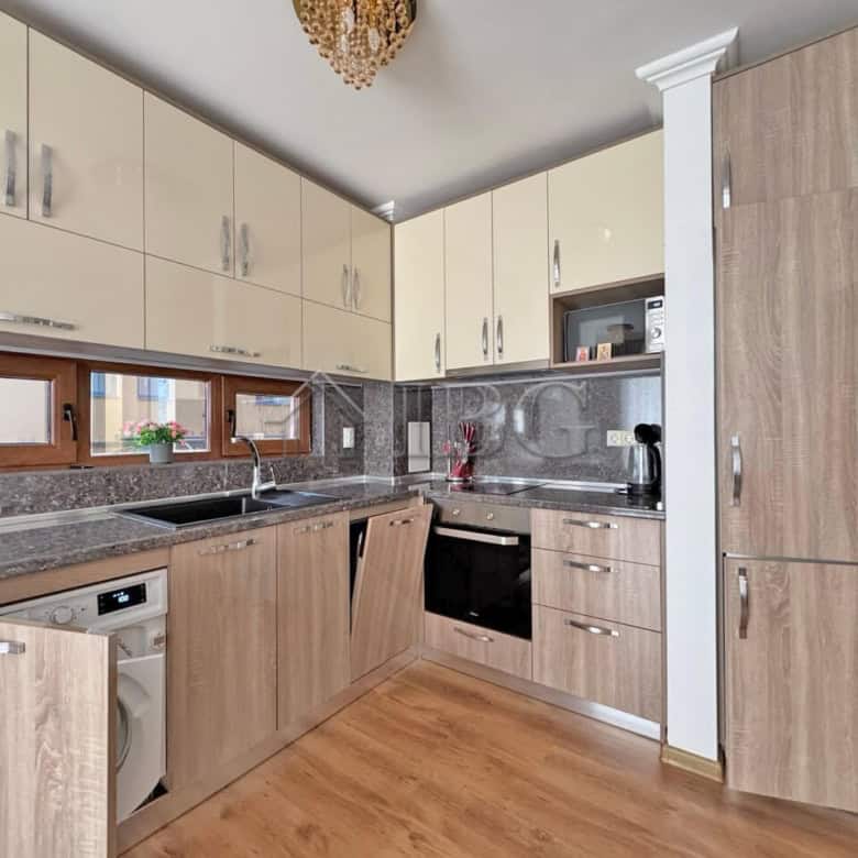 Modern kitchen with wooden cabinets, sink, oven, and washing machine.