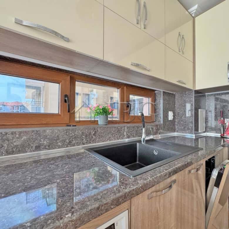 Bright kitchen with granite surfaces, wooden cabinets, and a view of neighboring buildings in Sveti.