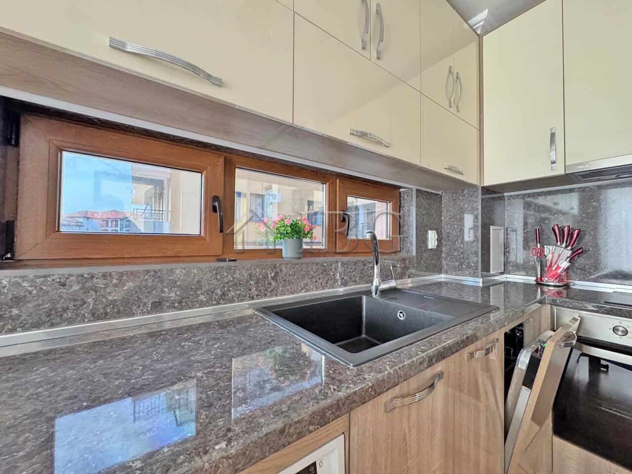 Bright kitchen with granite surfaces, wooden cabinets, and a view of neighboring buildings in Sveti.
