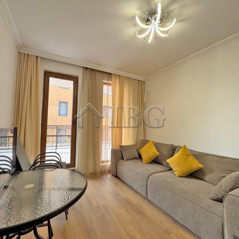 Spacious living room with sofa and yellow cushions, large windows with curtains, and a modern chande.