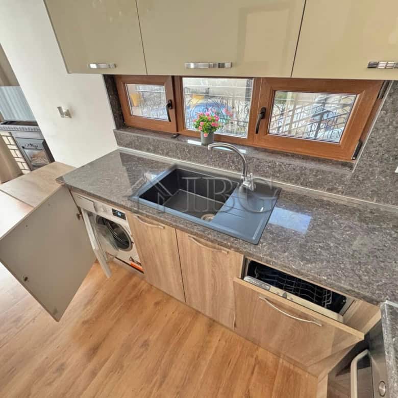 Kitchen with wooden cabinets, granite countertops, and a window view in Sveti Vlas.