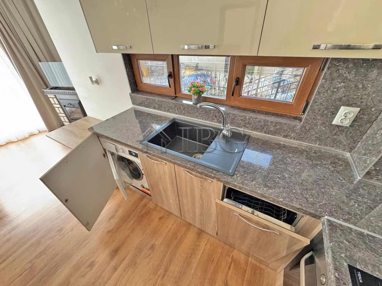 Kitchen with wooden cabinets, granite countertops, and a window view in Sveti Vlas.