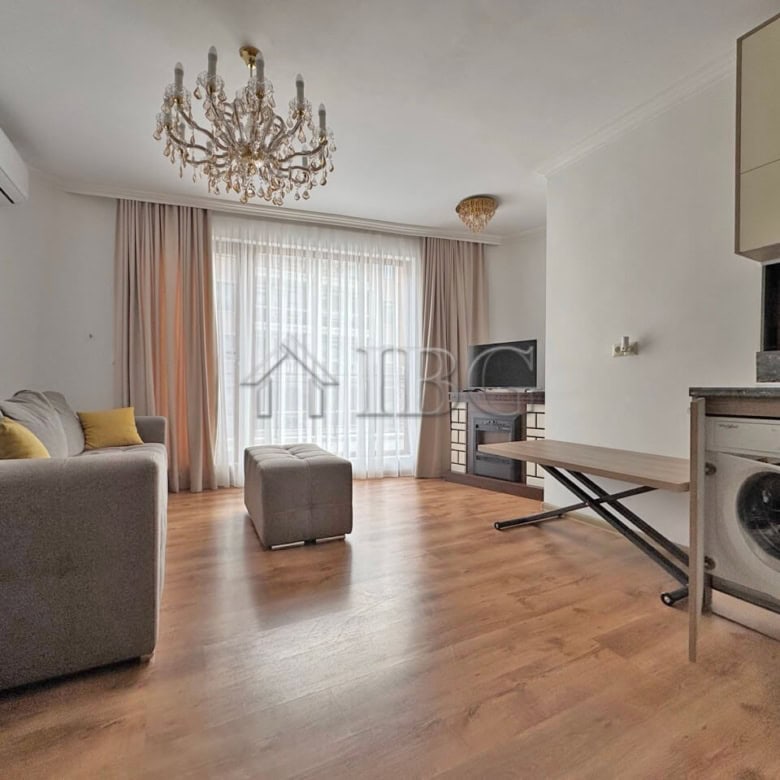 Bright living room with pool view, sofa, chandelier, and kitchen area in Sveti Vlas apartment.