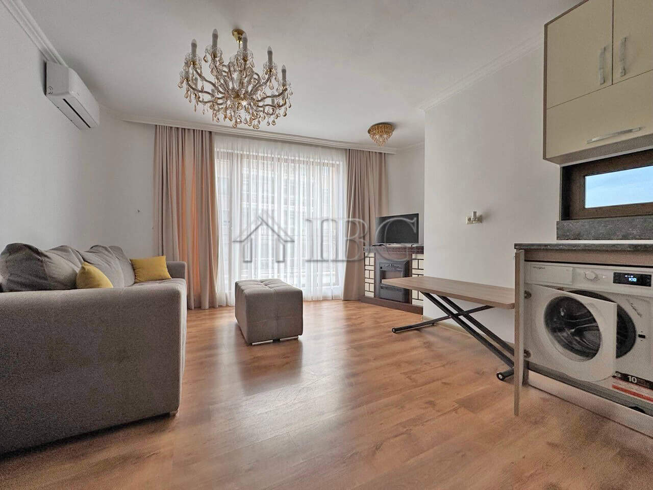 Bright living room with pool view, sofa, chandelier, and kitchen area in Sveti Vlas apartment.