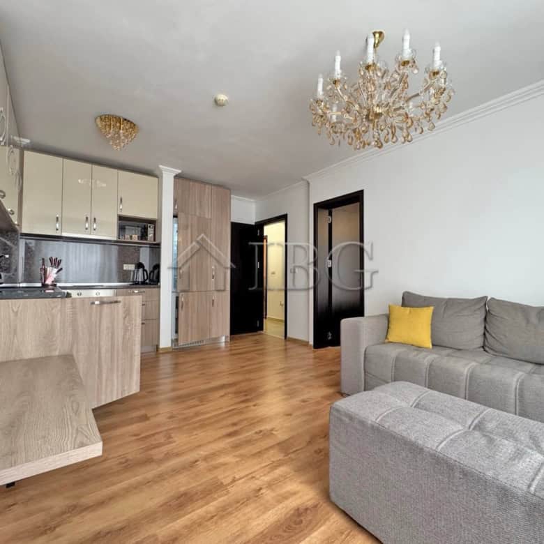 Bright living room with sofa, chandelier, and open kitchen in Sveti Vlas apartment.
