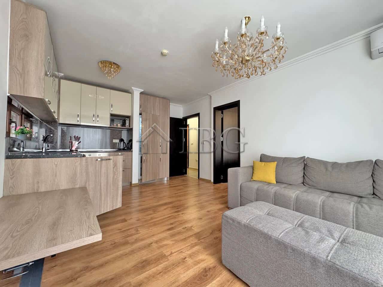 Bright living room with sofa, chandelier, and open kitchen in Sveti Vlas apartment.