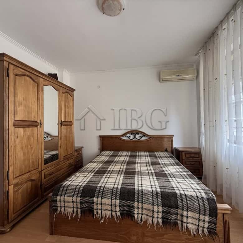 Bright, airy bedroom with wooden furniture and large windows in Tili Complex, Aurelia District, Ness.