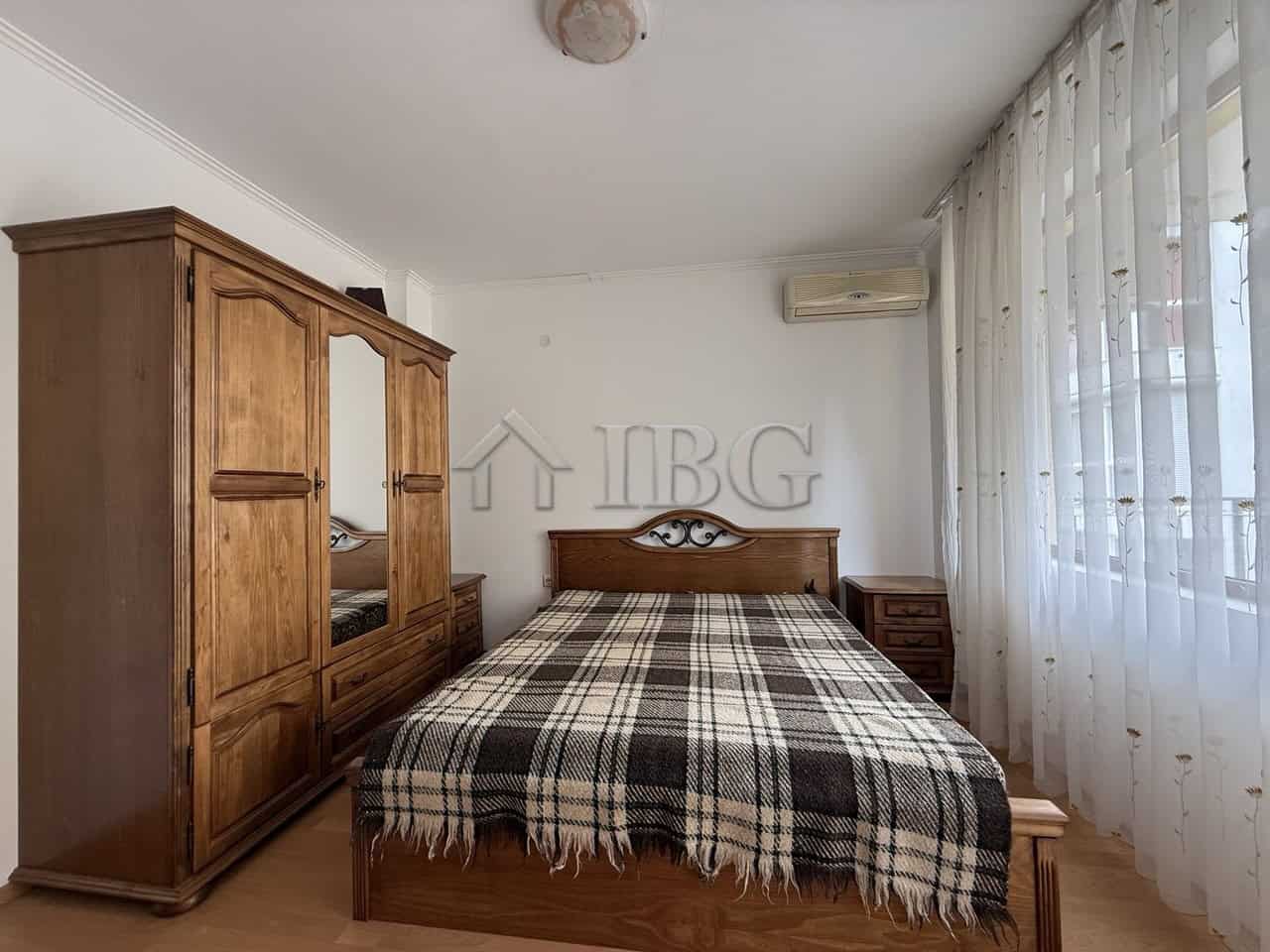 Bright, airy bedroom with wooden furniture and large windows in Tili Complex, Aurelia District, Ness.