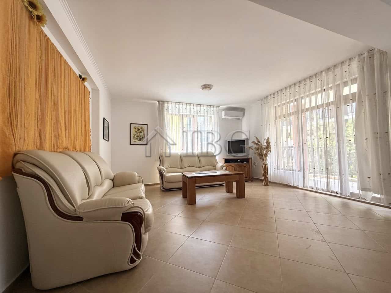 Bright living room with large windows and elegant furniture in Tili Complex, Aurelia District, Nesse.