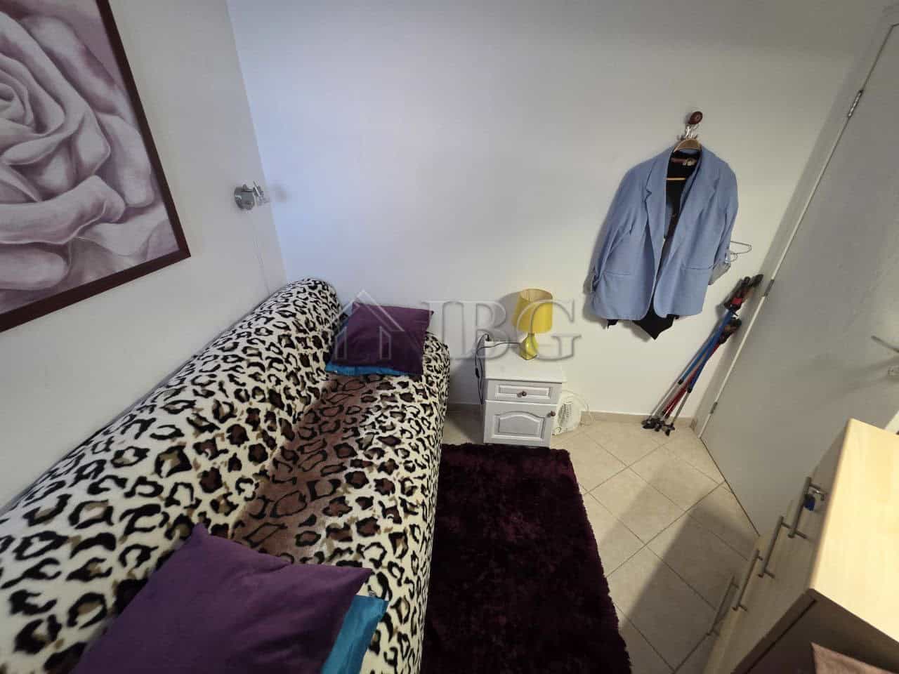 Leopard print sofa with purple cushions in a compact living space.