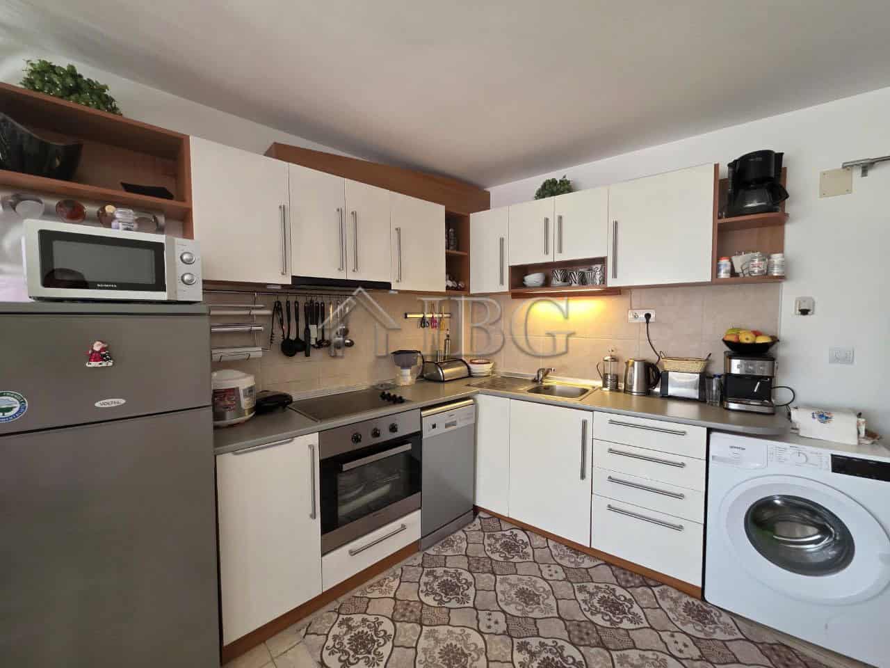 Bright, fully equipped kitchen with white cabinets and stainless steel appliances in Ravda resort.
