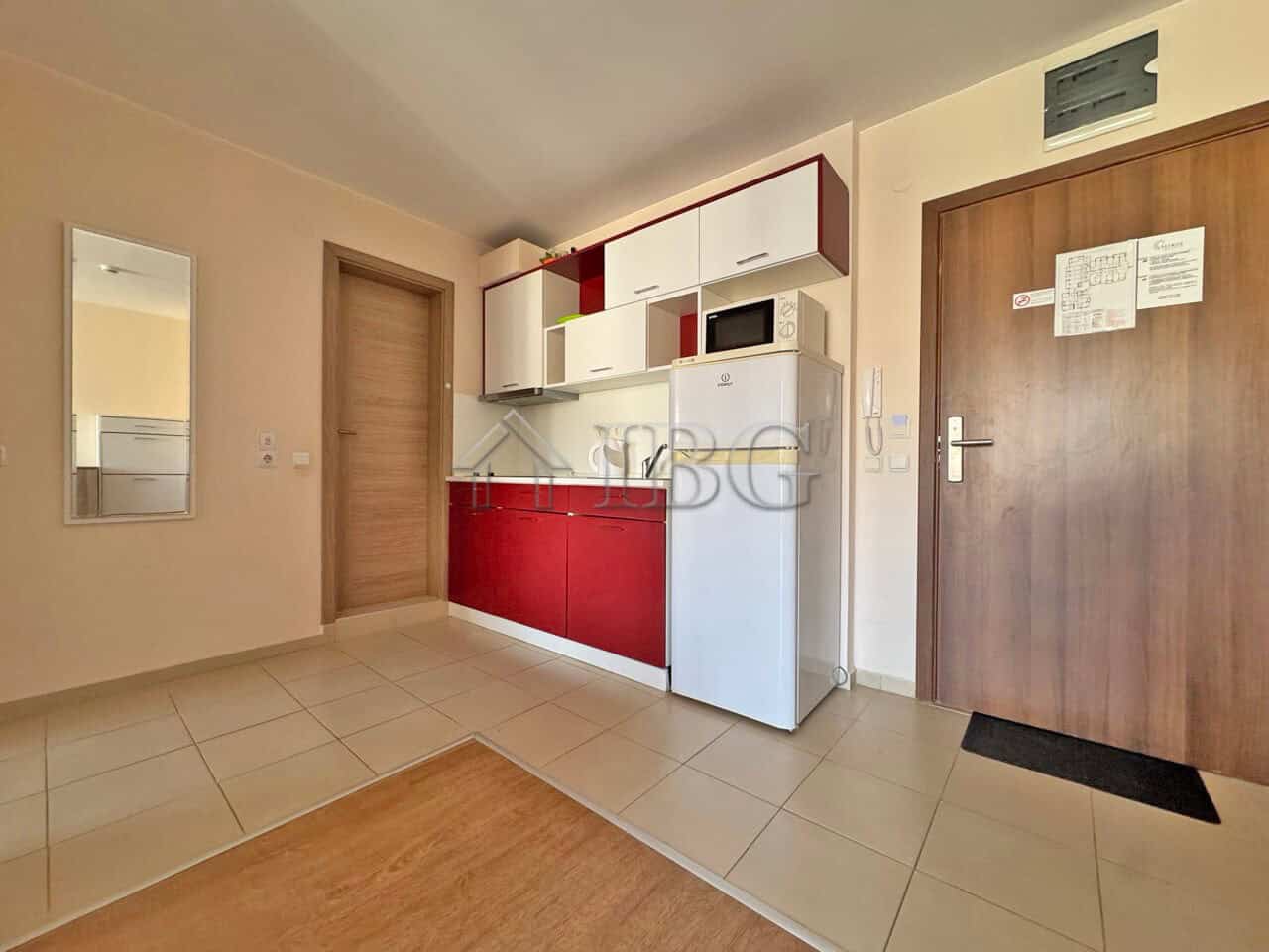 Modern kitchen in Sveti Vlas apartment for sale Kitchen with white and red cabinets, microwave, and refrigerator in Sveti Vlas property.