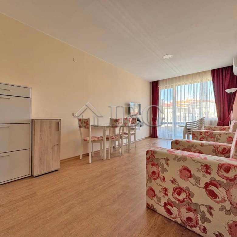 Bright living room with large windows and floral sofas.