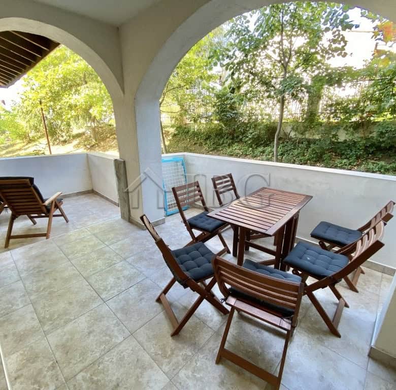 Terrace with outdoor dining set and lush greenery backdrop.