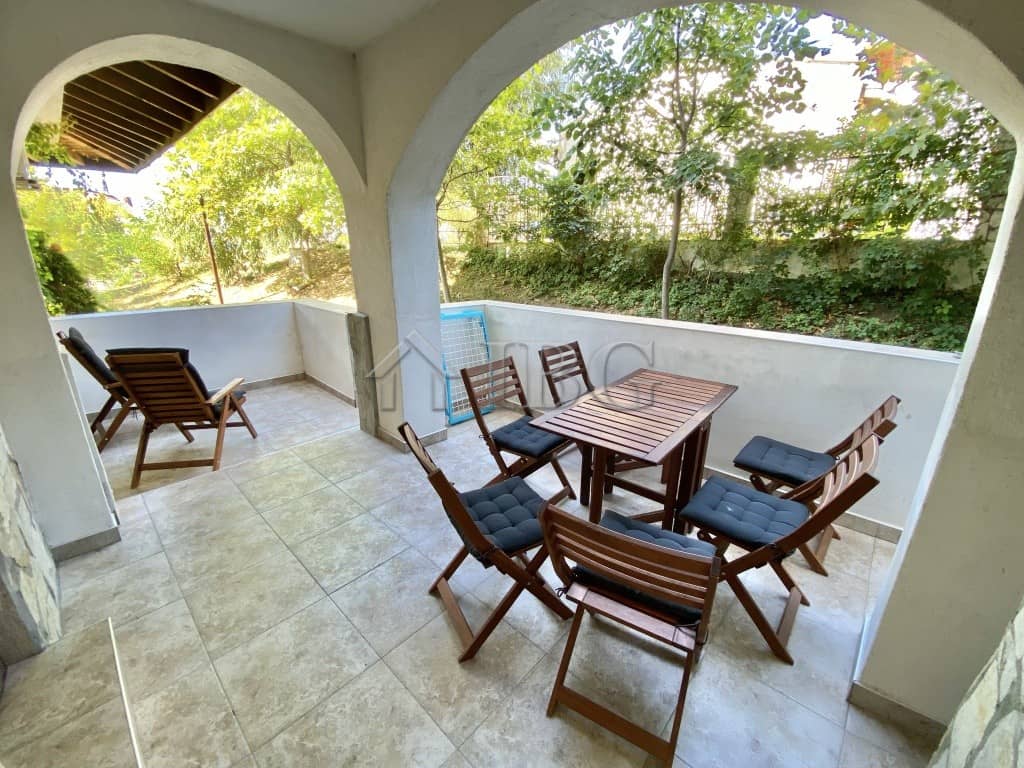 Terrace with outdoor dining set and lush greenery backdrop.