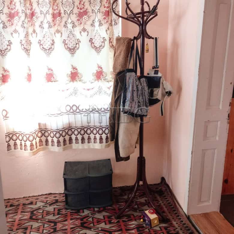 Interior view showing a coat rack, curtains, and a storage box near a window.