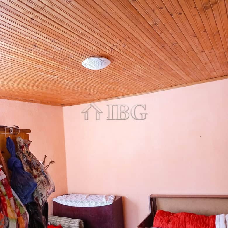 Interior of a bedroom featuring a wooden ceiling, pink walls, and basic furniture.