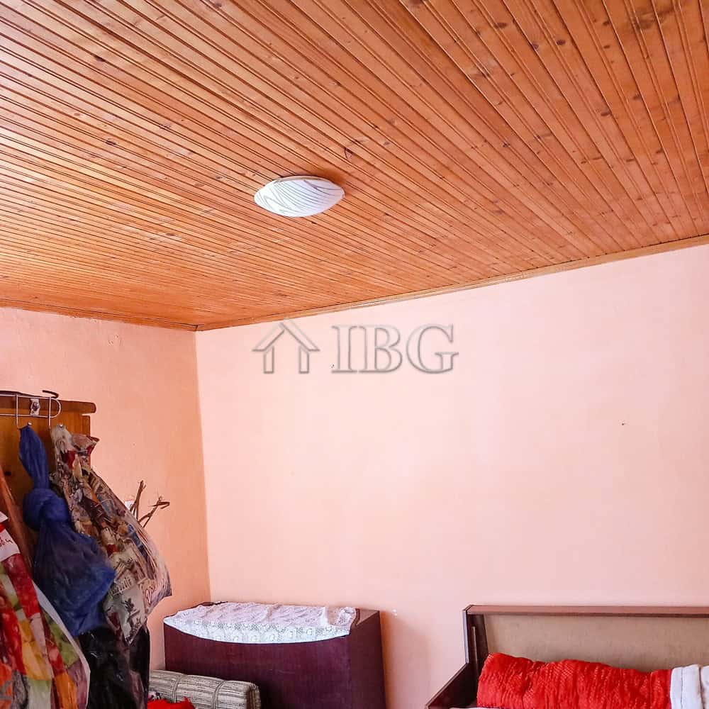 Interior of a bedroom featuring a wooden ceiling, pink walls, and basic furniture.