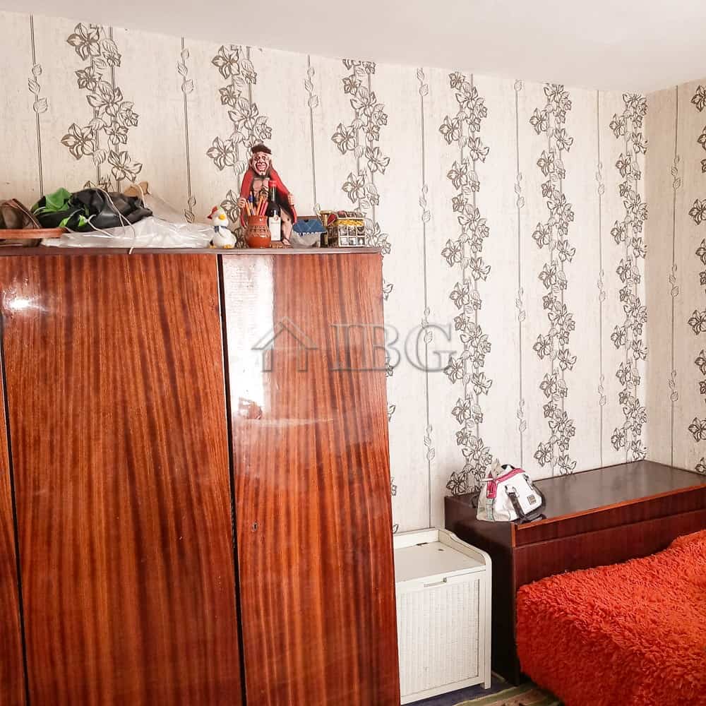 Interior of a bedroom featuring a large wooden wardrobe and a bed with a red blanket.