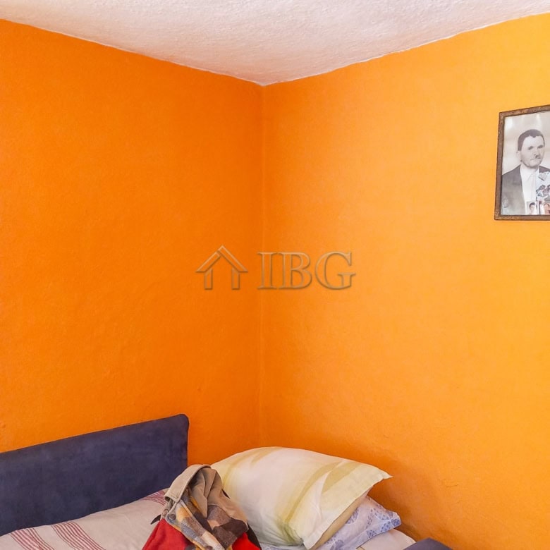 Bright interior of a 3-bedroom house with vibrant orange walls and a comfortable bed.