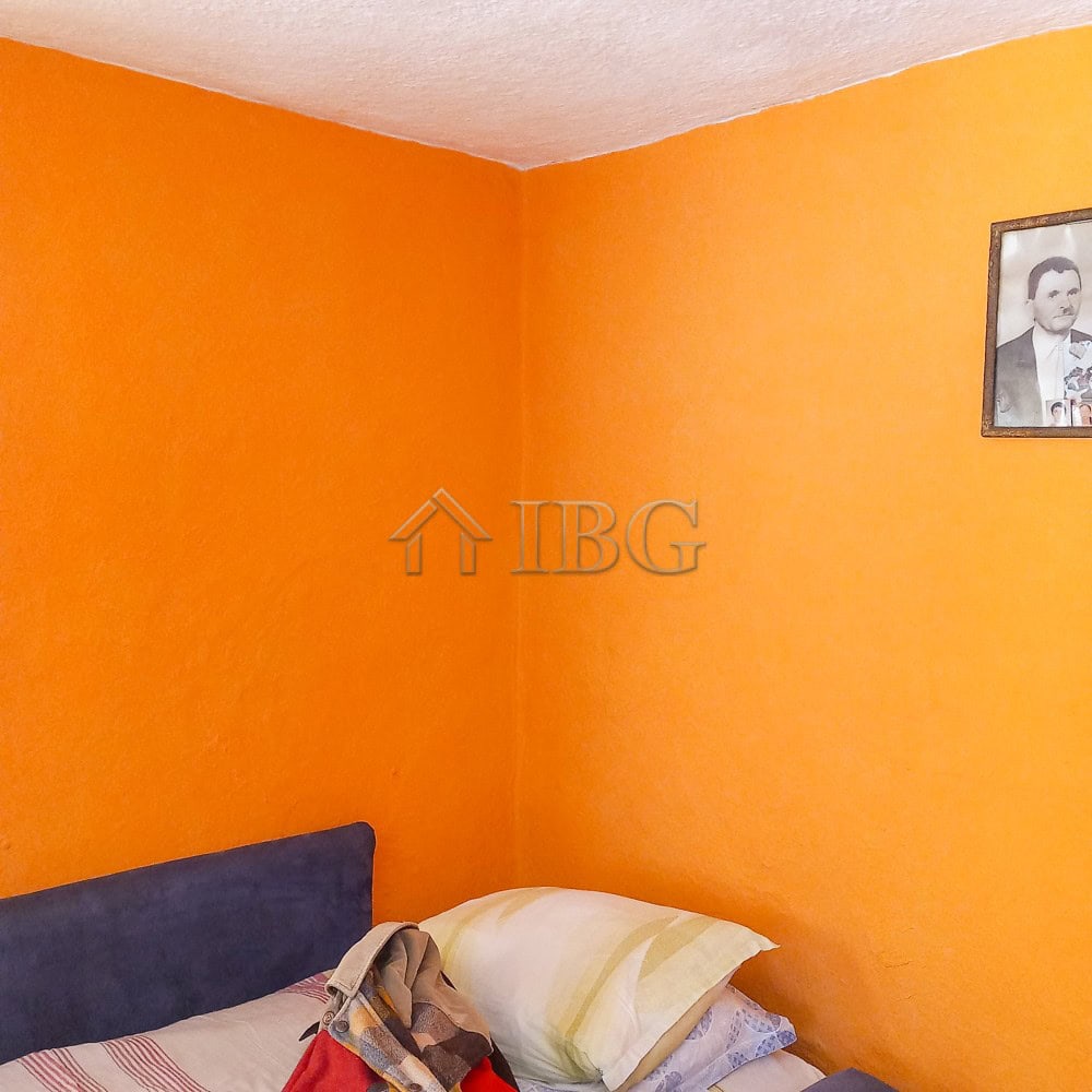 Bright interior of a 3-bedroom house with vibrant orange walls and a comfortable bed.