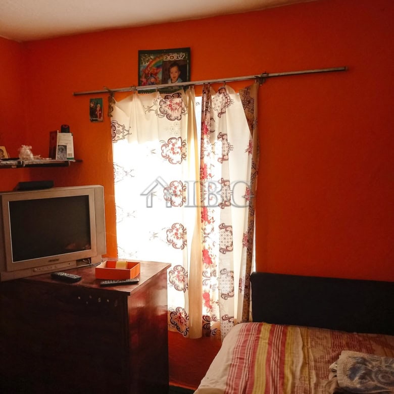 Interior view of a 3-bedroom house featuring a bright living room with a TV and floral curtains.